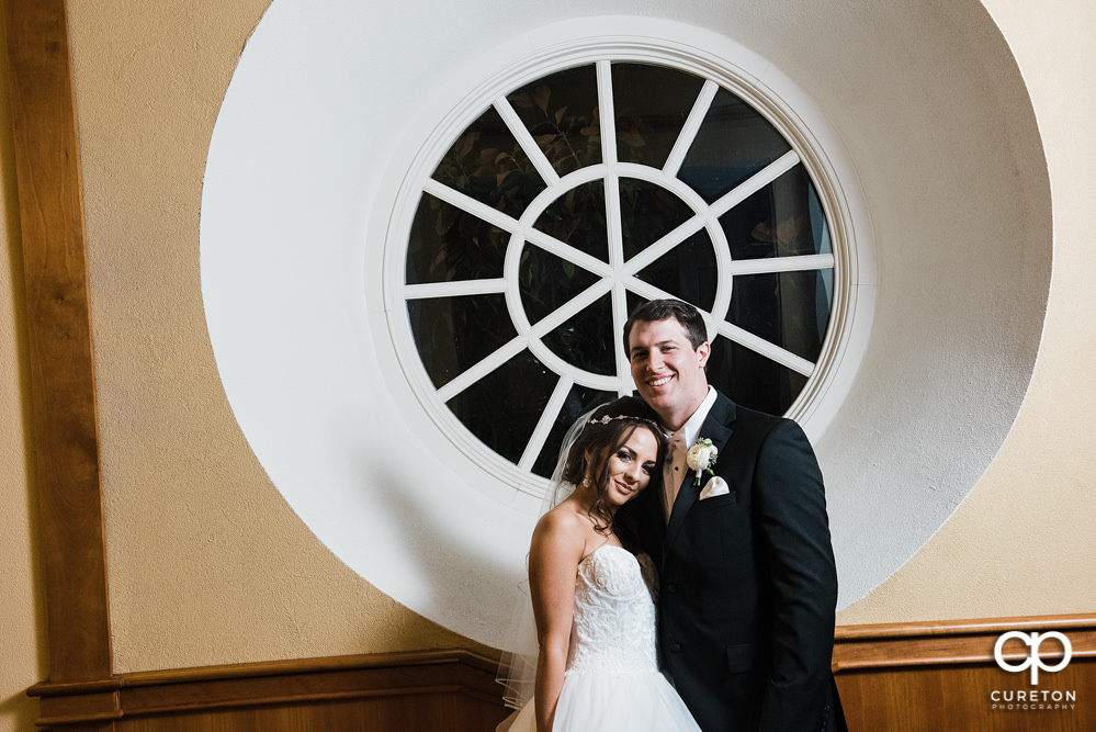 Bride and groom standing in a circular window.