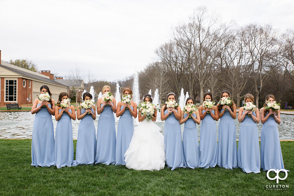 Bridesmaids with flowers over their faces.