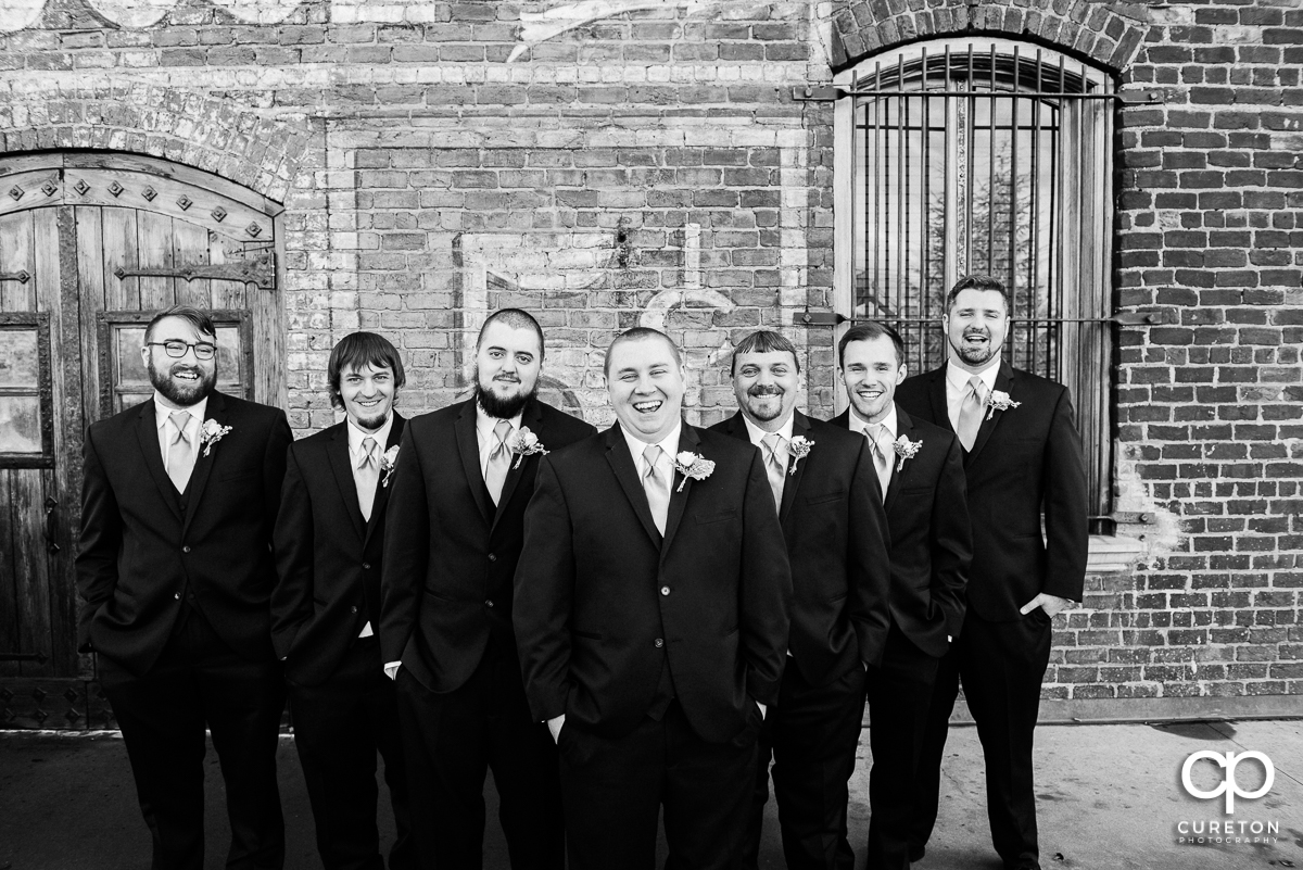 Groom and groomsmen laughing on the deck of The Old Cigar Warehouse.
