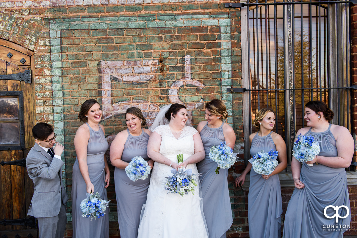Bride and bridesmaids laughing holding winter bouquets on the deck of The Old Cigar Warehouse.