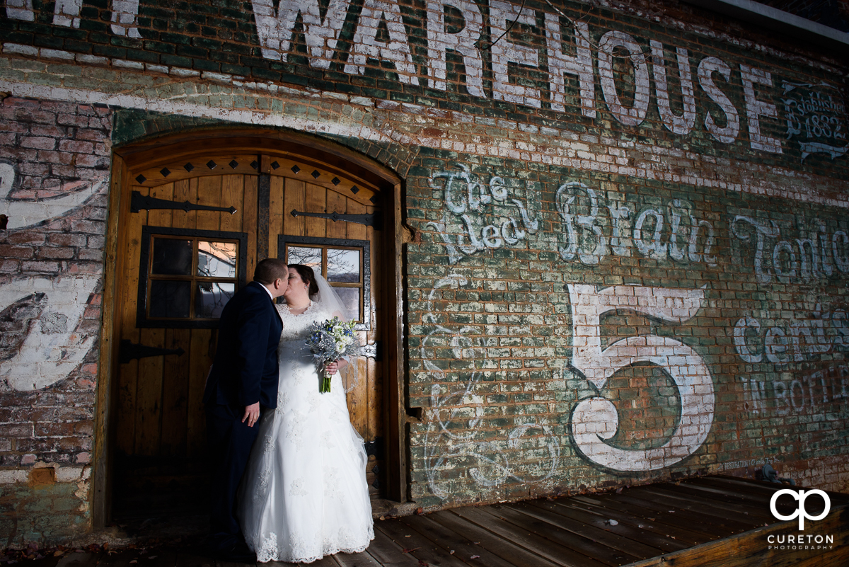 Bride and groom kissing on the back deck of The Old Cigar Warehouse.