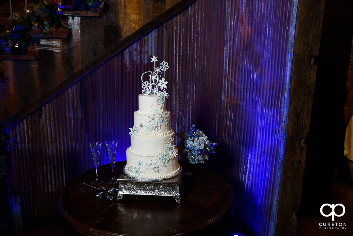 Winter themed wedding cake on a blue uplit backdrop.