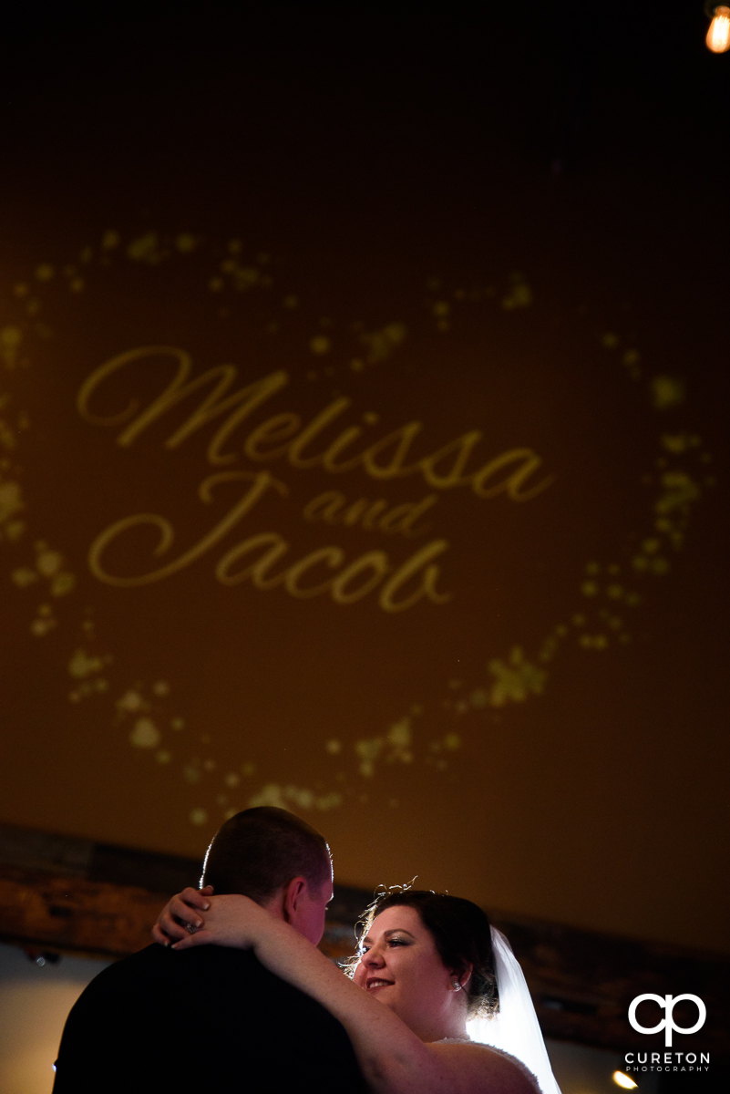 Bride and groom having their first dance with an animated logo in the background.