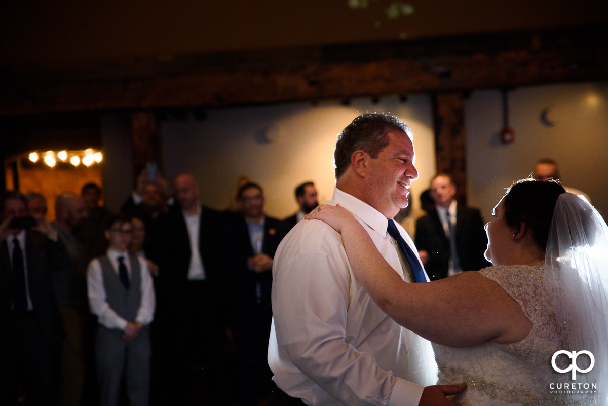 Dad smiling at his daughter as they share a dance at her wedding reception.