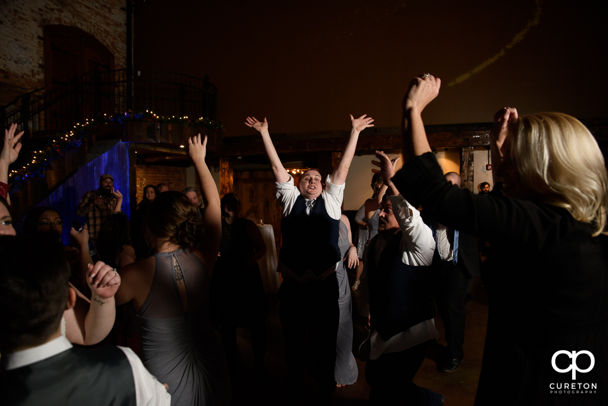 Groom dancing with his hands in the air.