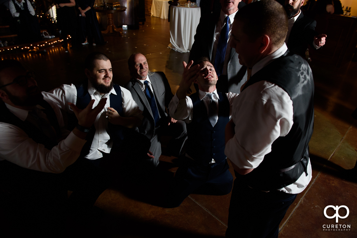 Groomsmen serenading the groom on the dance floor.