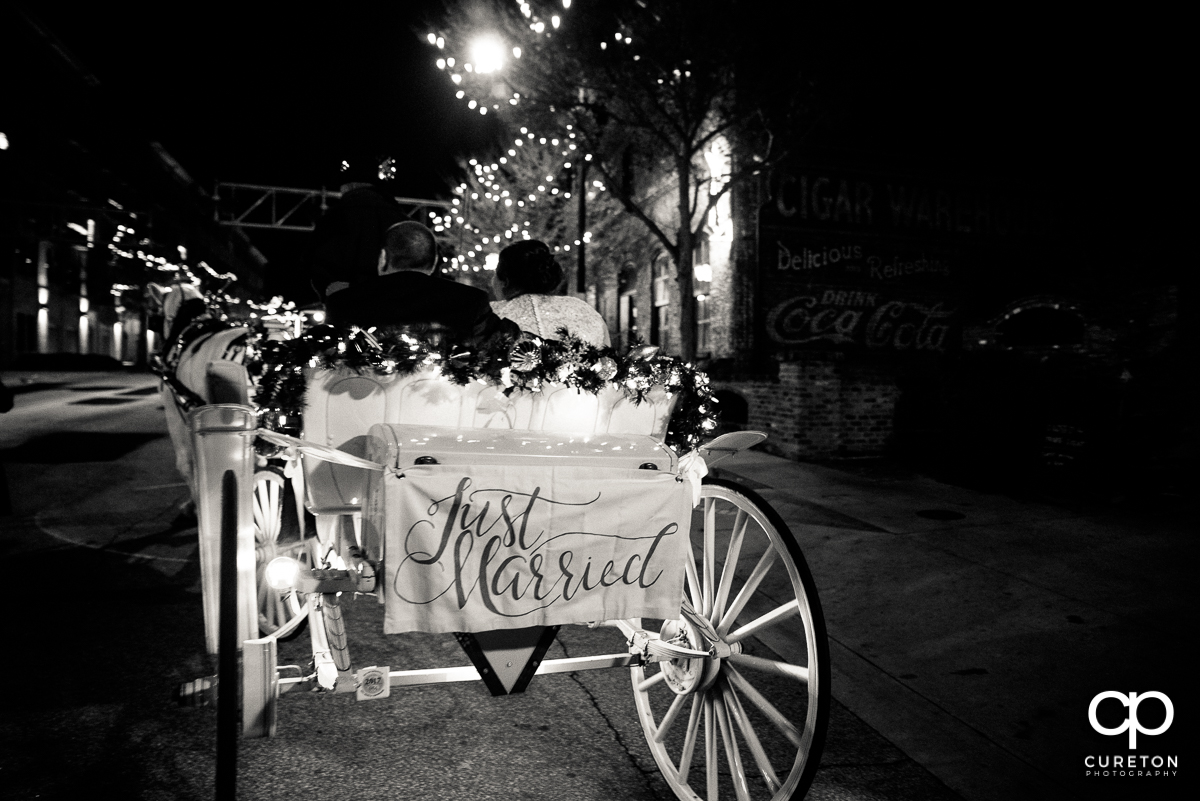 Bride and groom leaving the wedding in a horse drawn carriage in downtown Greenville.