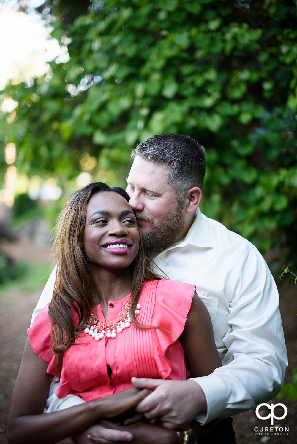 Future groom hugging his bride during their downtown Greenville park engagement session.