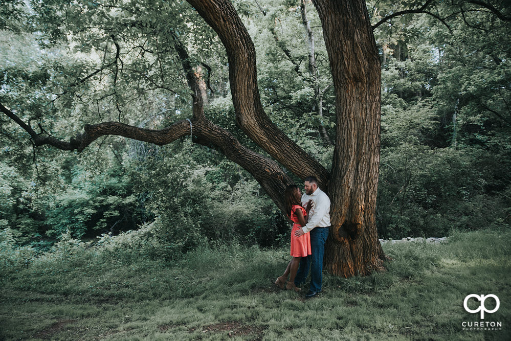 Engaged couple leaning on an oak tree during their downtown Greenville park engagement session.