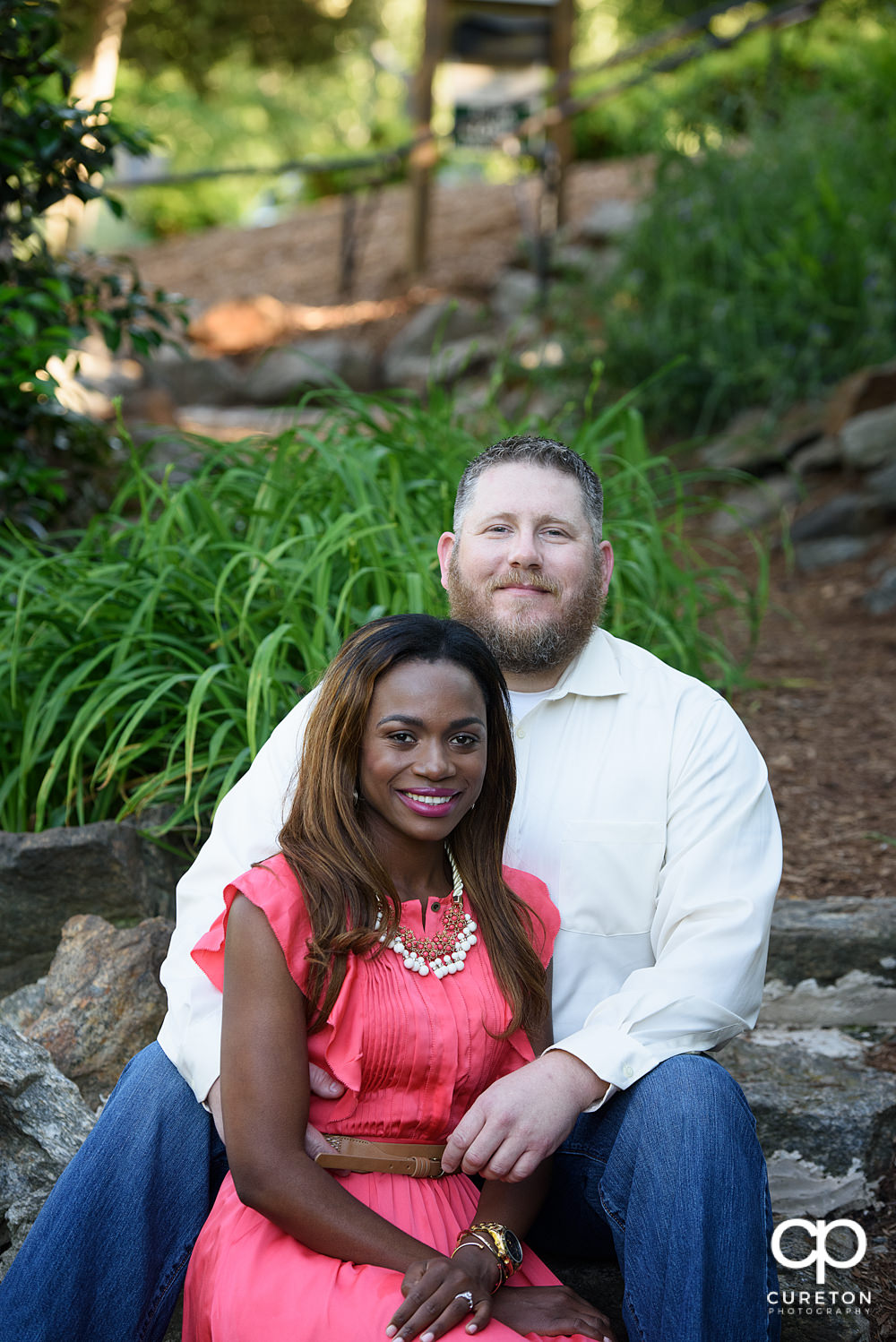 Future bride and groom sitting in the steps in the park.