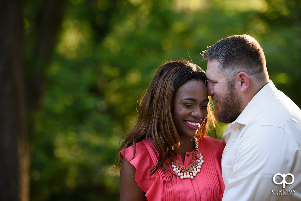 Couple smiling at their engagement session in a park in downtown Greenville.