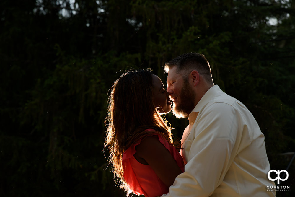 Engaged couple kissing at sunset.