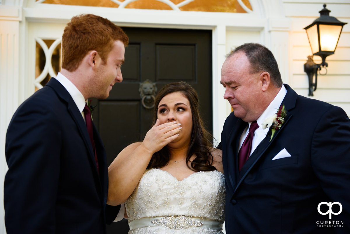 Bride crying while having a first look with her dad and brother before her wedding ceremony.