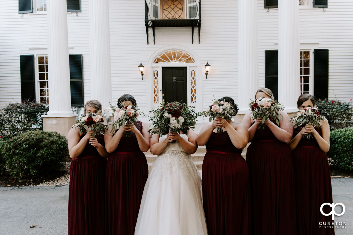 Brides holding flowers in front of their faces.