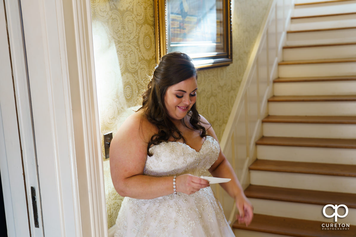 Bride smiling while reading a letter from her groom.