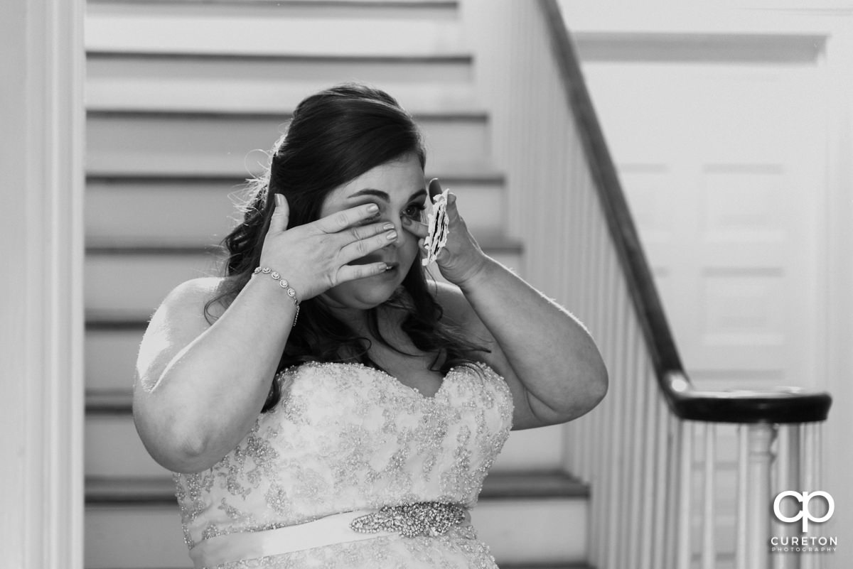 Bride wiping tears after reading a letter from her groom.