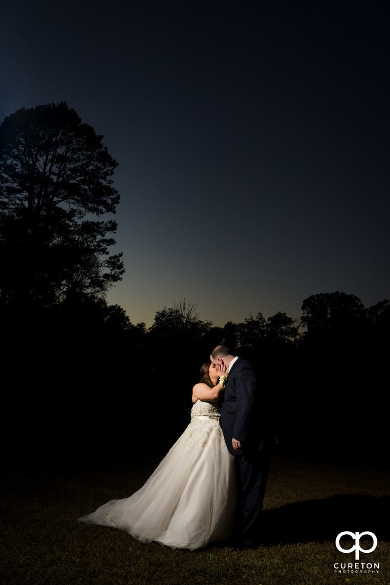 Bride and groom kissing at sunset.
