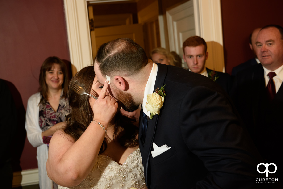 Bride wiping icing on the grooms face as they cut the cake,
