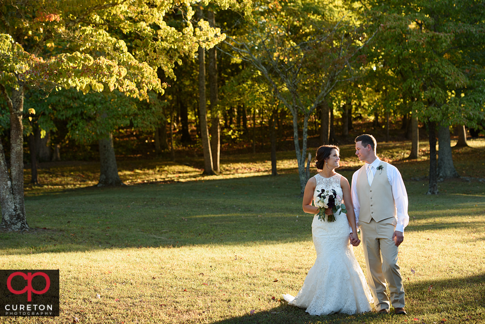 Bride and groom walking in the fall leaves.