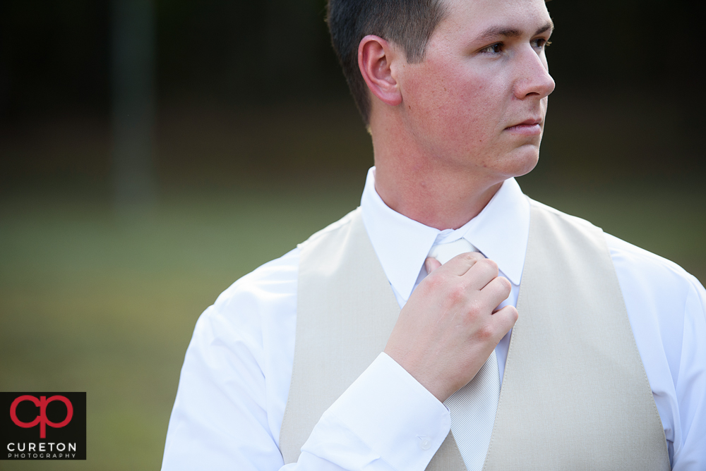 Groom adjusting his tie.