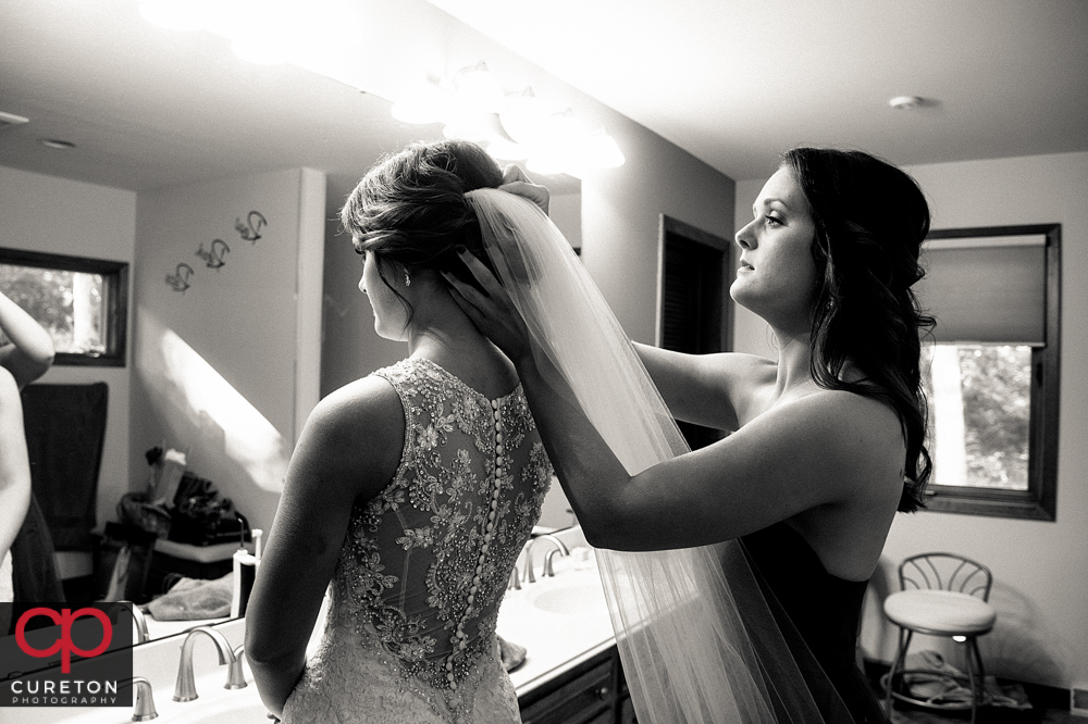 Bride's sister helps her with the veil.