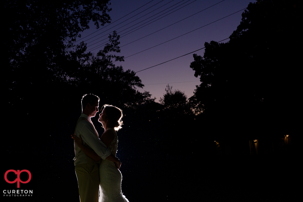 Bride and groom at sunset under a purple sky.