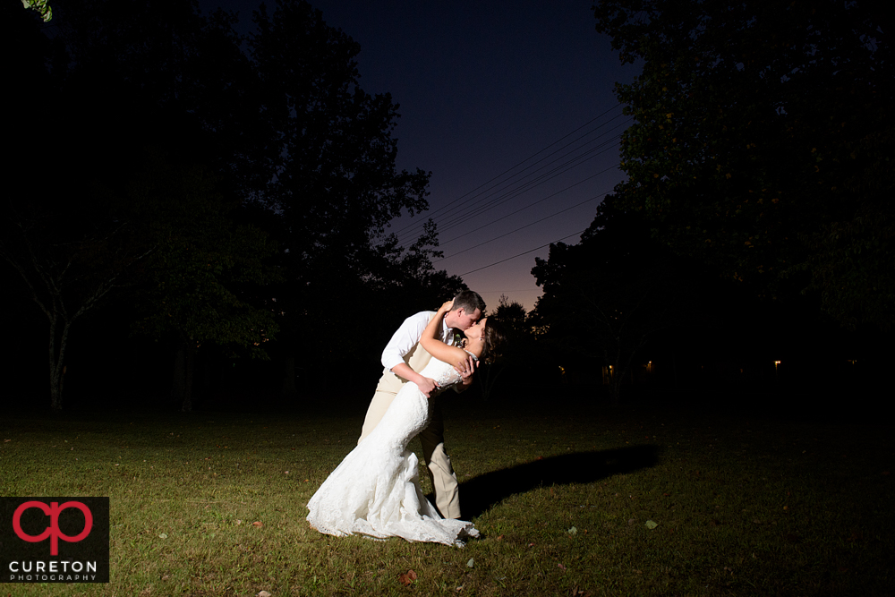 Groom dipping his bride at sunset.