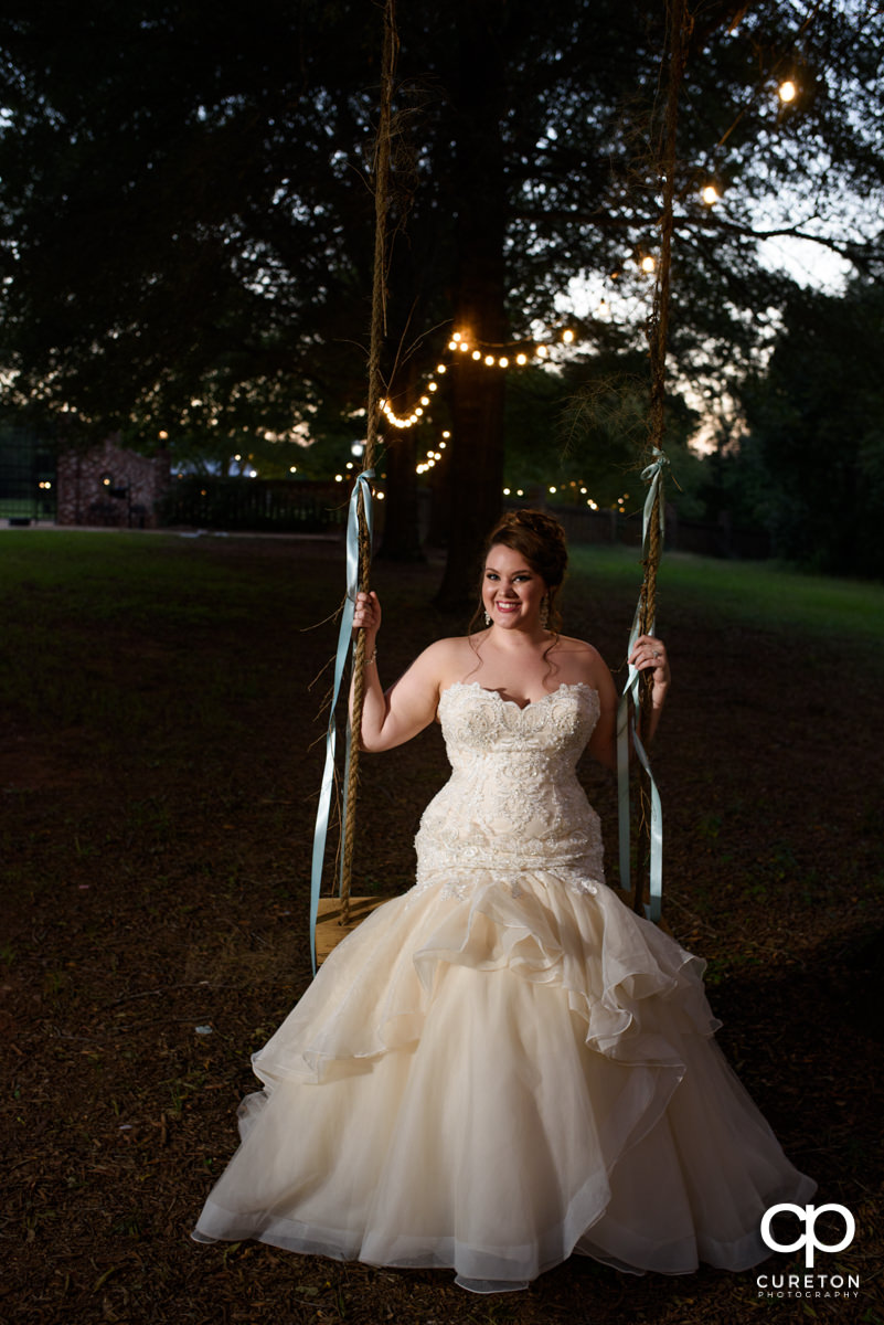 Bride sitting on a tree swing.