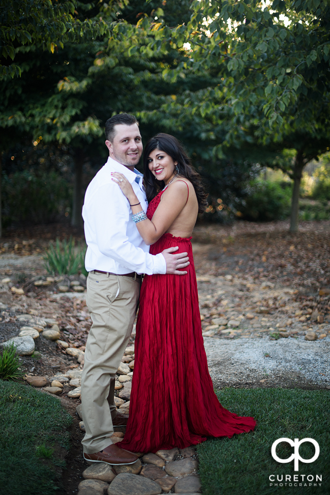 Groom with his future bride wearing a bright red dress during their engagement session.