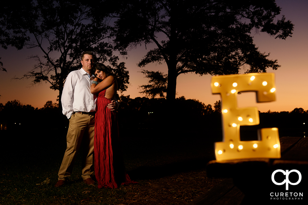 Bride and groom with a lit letter of their initial.