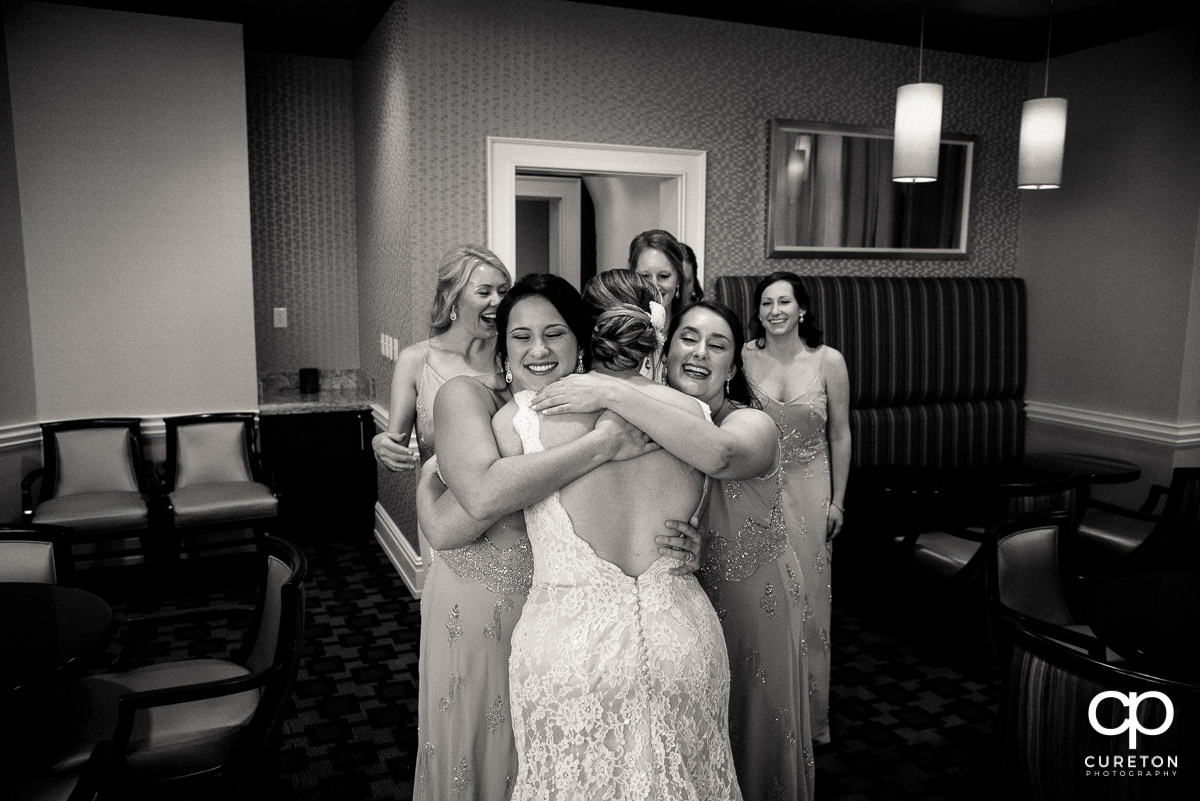 Bridesmaids hugging the bride.