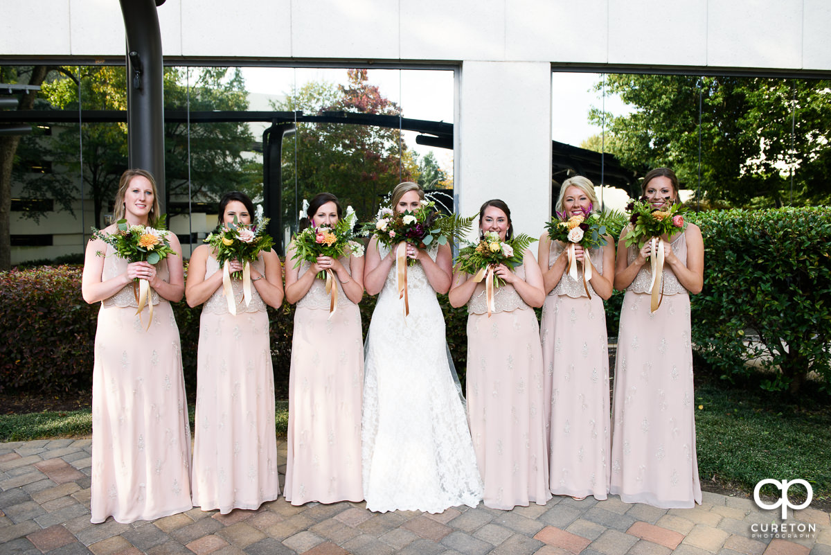 Bridesmaids holding flowers up to their faces.