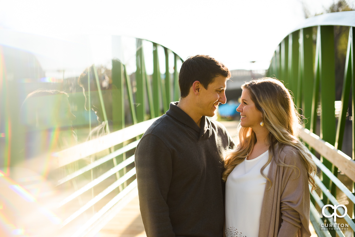 Engaged couple on a bridge over the Reedy River.