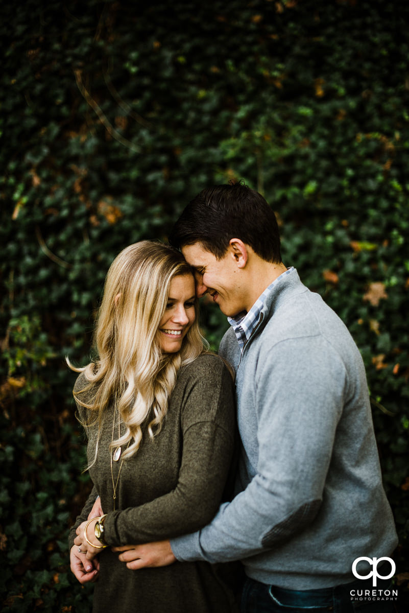 Man and his future bride cuddling during a fall engagement session.