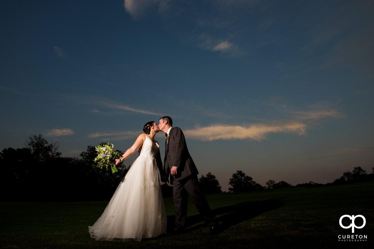 Bride and groom kissing on the golf course after their Holly Tree Country Club wedding.