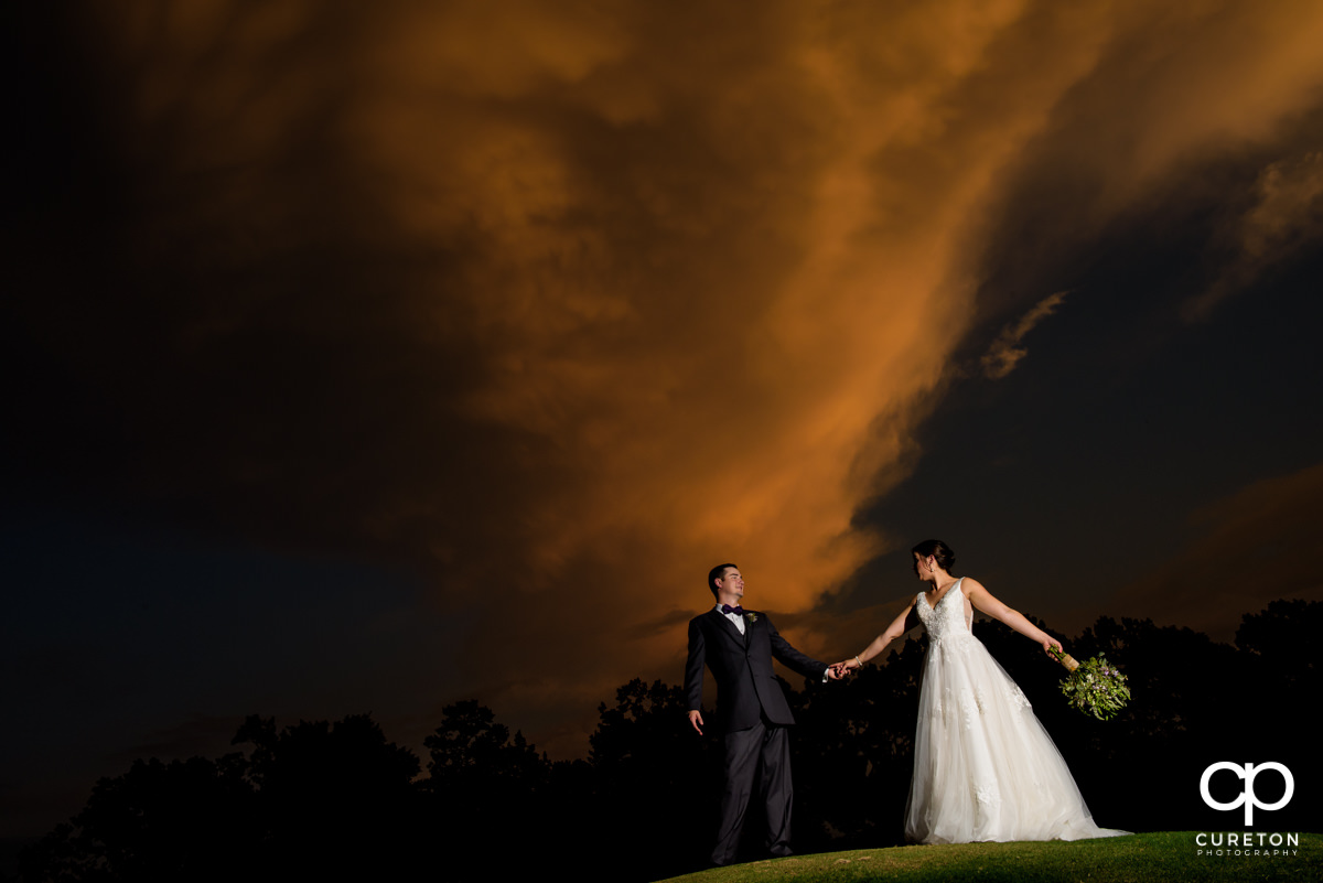 Bride and groom holding hands at sunset after their Holly Tree wedding in Simpsonville,SC.