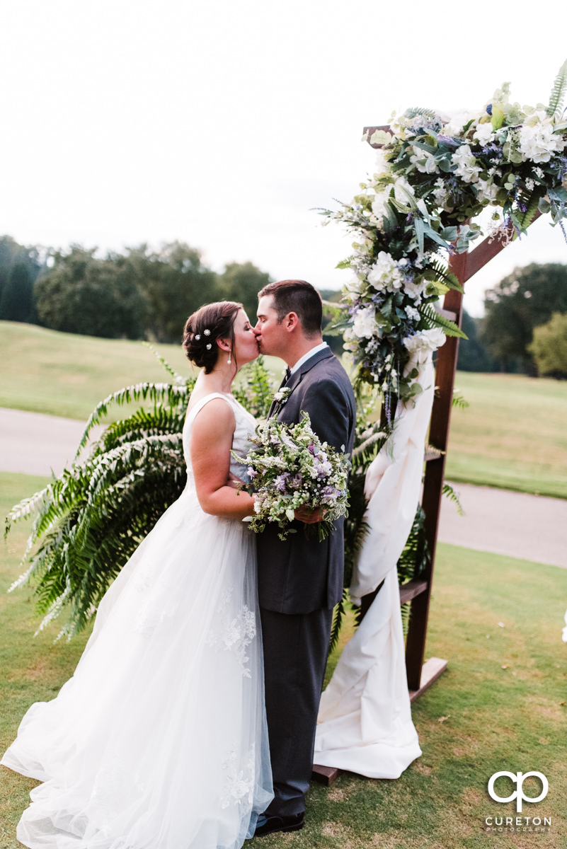 Newlyweds kissing after their wedding ceremony at Holly Tree Country Club.
