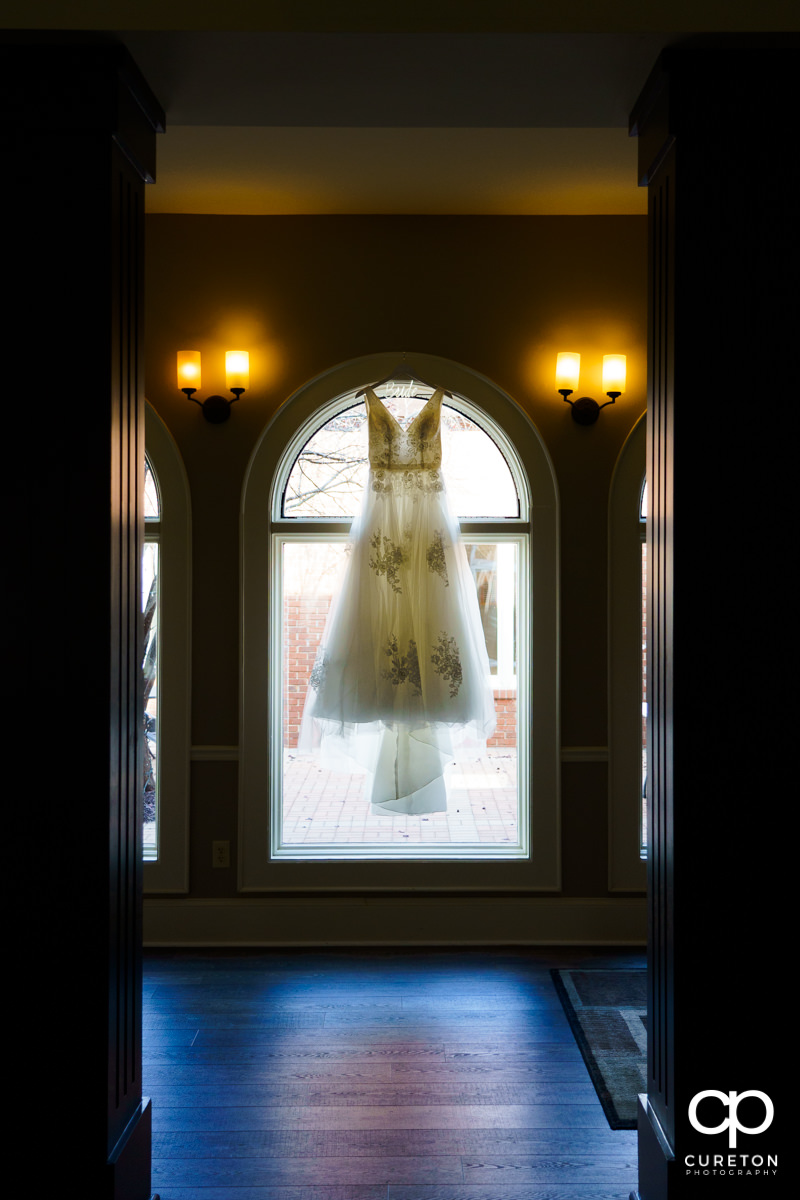 Bride's dress hanging in a window.