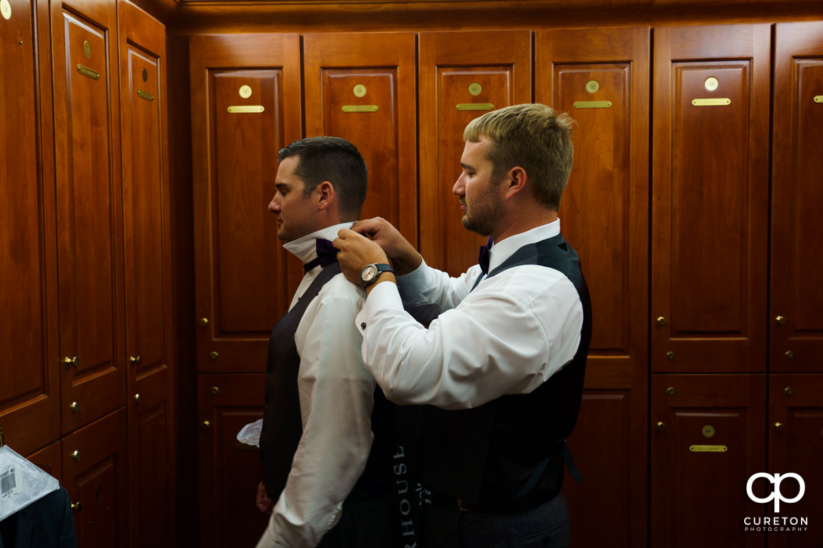 Groom's brother helping him with his tie.