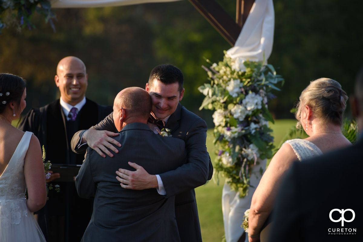 Groom hugging the bride's father at the ceremony.