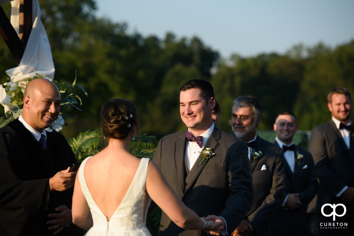 Groom smiling at his bride during the ceremony.