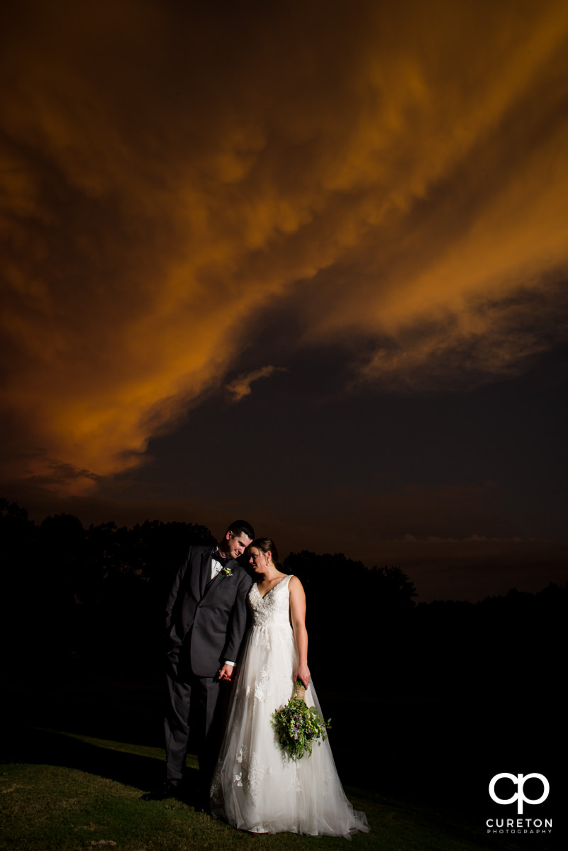 Newlyweds leaning into each other at sunset after their Holly Tree Country Club wedding ceremony.
