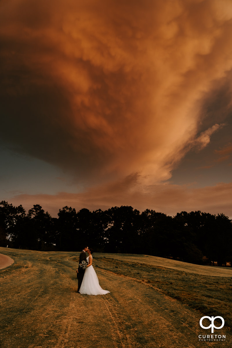Bride and groom on a golf course at sunset.