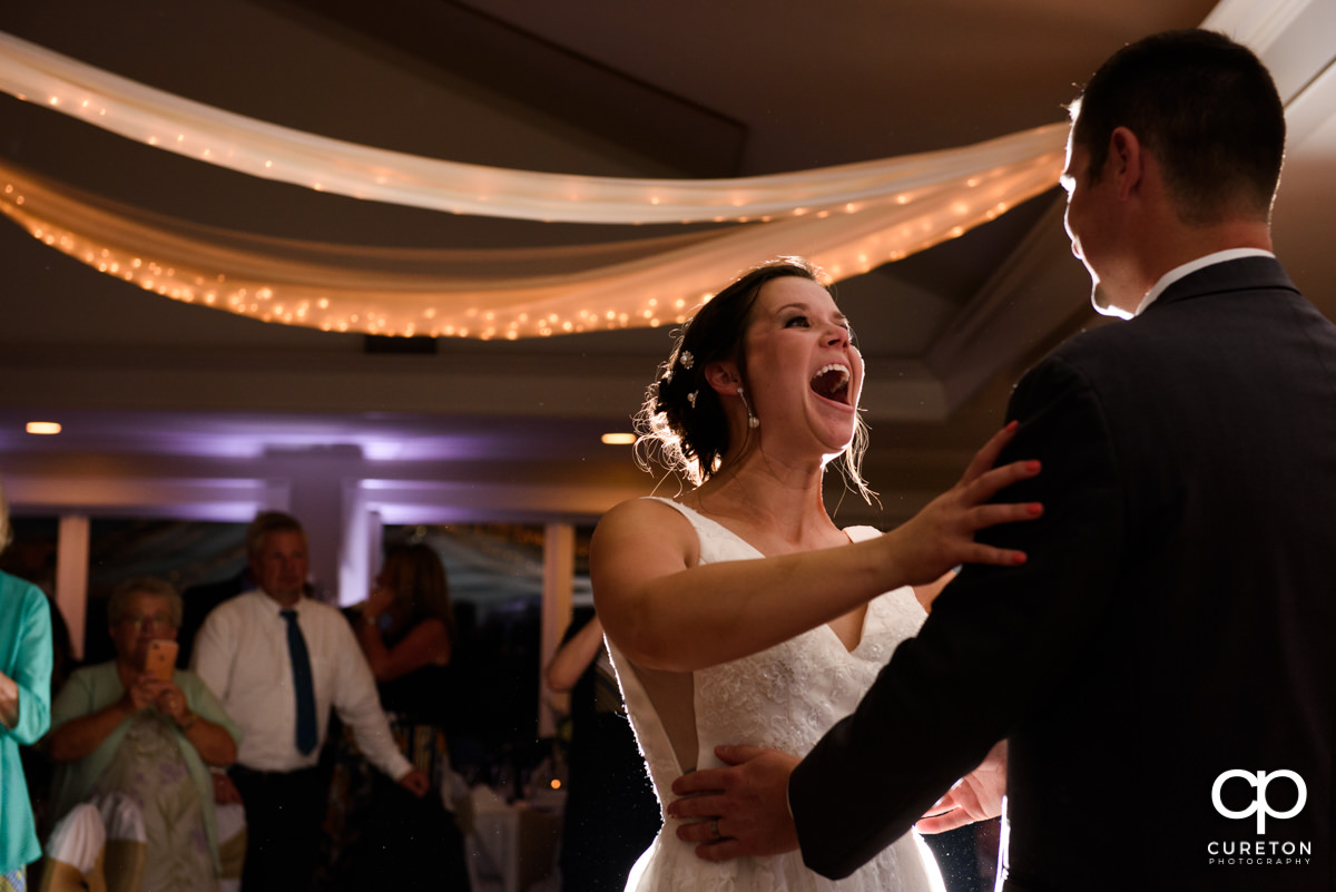 Bride smiling and laughing at the groom during their first dance at their Holly Tree Country Club wedding reception.