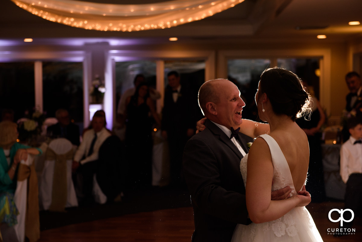 Bride's father smiling at his daughter during their dance at the wedding reception.