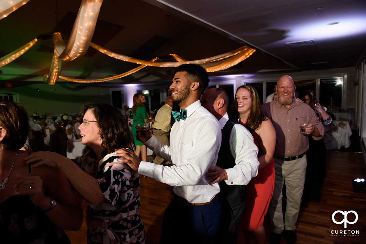 Wedding guests dancing a train at the reception.