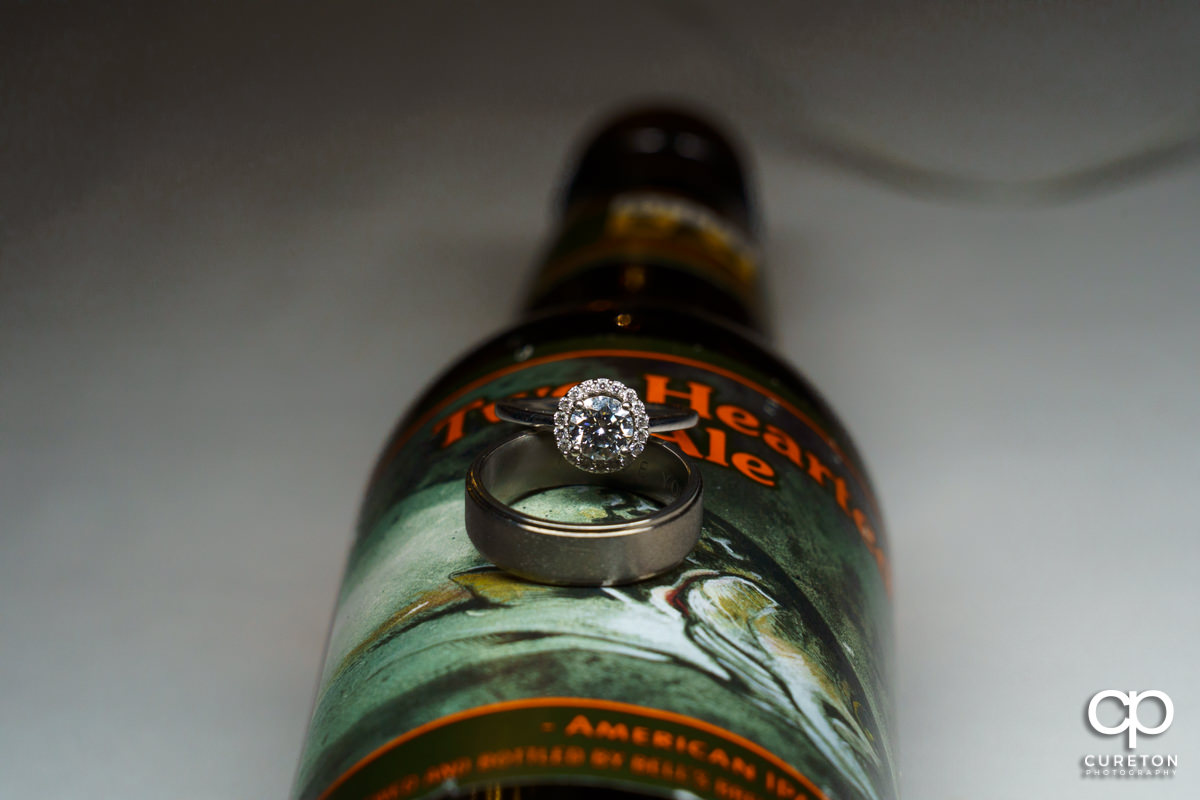 Wedding rings on a bottle of beer closeup.