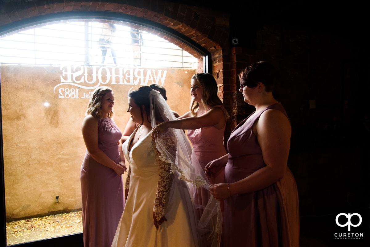 Bridesmaids helping the bride into her wedding dress before the ceremony at The Old Cigar Warehouse.