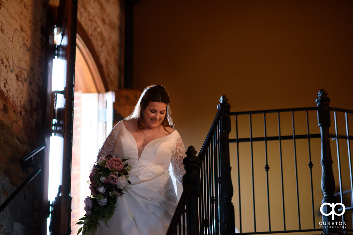 Bride making a grand entrance down the staircase into the wedding ceremony at The Old Cigar Warehouse in Greenville.