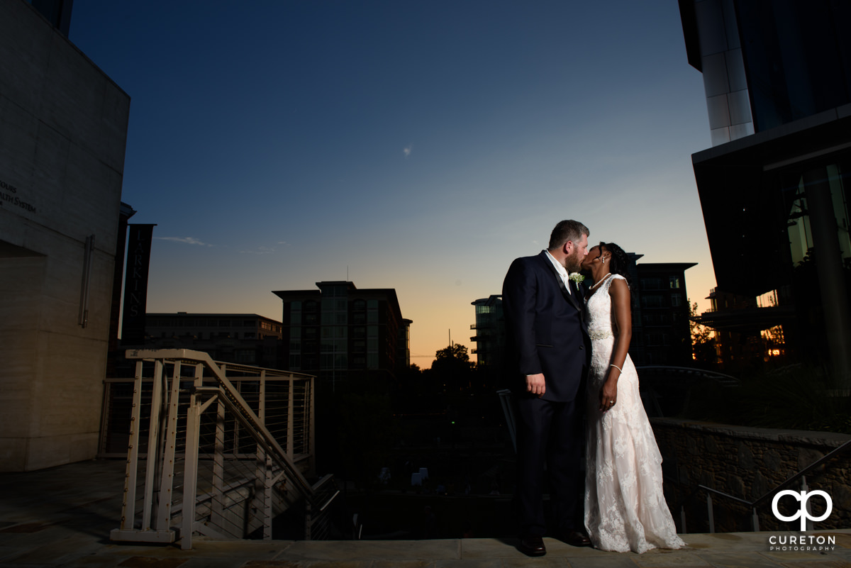 Bride and groom kissing at sunset outside of Larkin's on the River before their wedding reception.